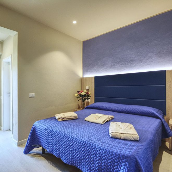 Camera vistamare suite, letto matrimoniale con copriletto blu e portafinesta con vista sul mare Camera vistamare suite, letto matrimoniale con copriletto blu e portafinesta con vista sul mare