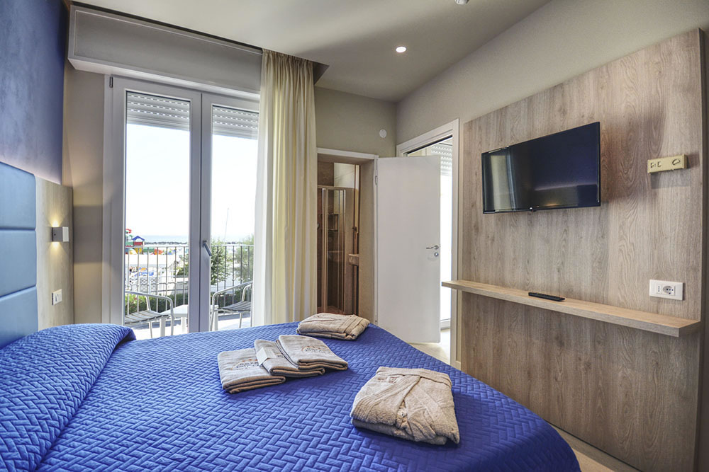 Chambre suite avec vue sur la mer, lit double et lits superposés avec couvre-lit bleu Chambre suite avec vue sur la mer, lit double et lits superposés avec couvre-lit bleu