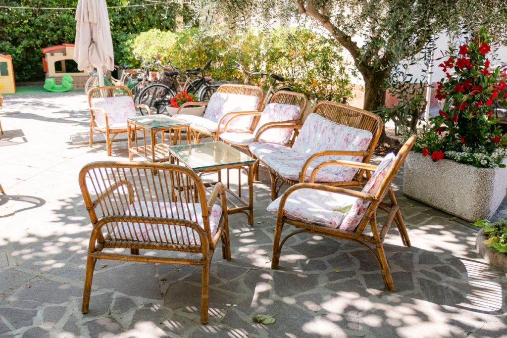 Giardino con comode sedie in vimini e tavolini all'ombra degli alberi