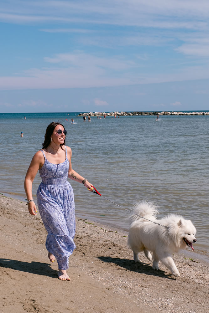 ragazza cammina in riva al mare col proprio cane