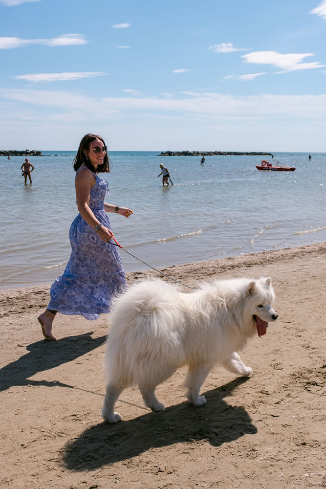 ragazza cammina in riva al mare col proprio cane