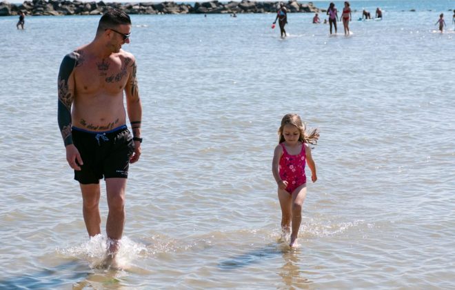 Père se promenant avec sa petite fille à marée basse