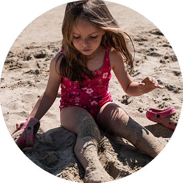 Mädchen spielt mit Sand am Strand Une fille joue avec le sable sur la plage